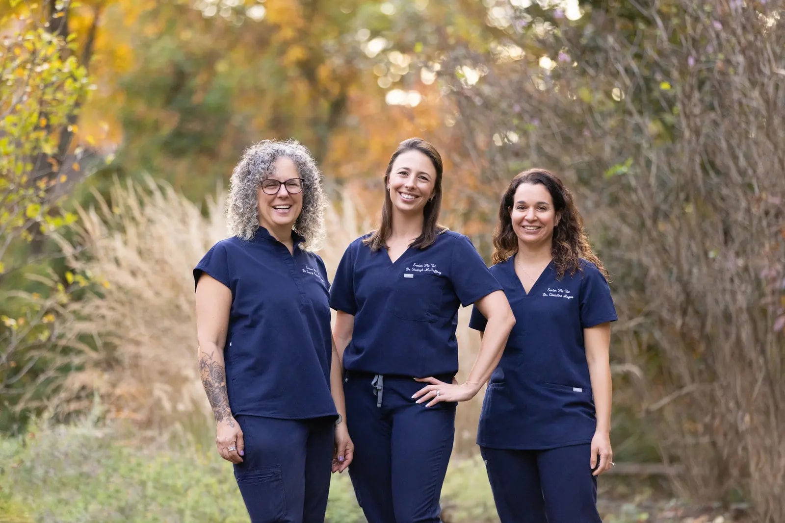 Drs. Cohen-Grady, McCaffrey, and Asgar of Senior Pet Vet standing together outdoors in their practice scrubs